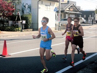 円谷幸吉メモリアルパーク前の道路を3人の男性ランナーたちが走っている様子の写真