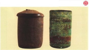 右上に21と番号が振られた、蓋付きの焦げ茶色の陶製の筒と、青銅製経筒が並んだ写真