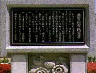 灰色の石製台座に黒い金属板が取り付けられ、縦書きの日本語で複数行の文章が刻まれており、下部には花の彫刻が施された市民憲章碑の写真