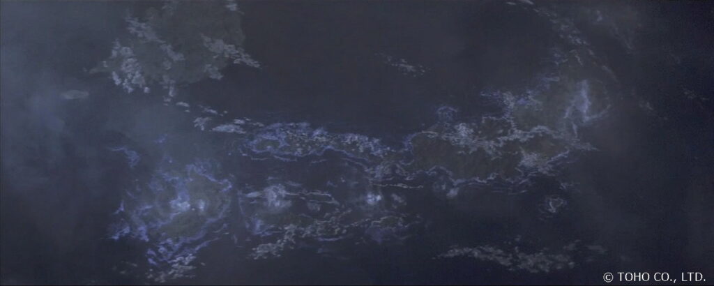 宇宙から見下ろした日本列島のシルエットが夜の闇に浮かび上がっており、沈みゆく列島の輪郭に沿って青白い光が点滅し、周囲を漂う濃い霧が不穏な空気を醸し出している、壮大なスケールの特撮映画の本編シーンを捉えた写真