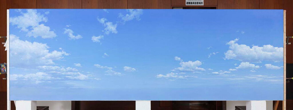 抜けるような青空に、幾層にも重なる白い雲が奥行きを持って描かれた横長の背景画の写真