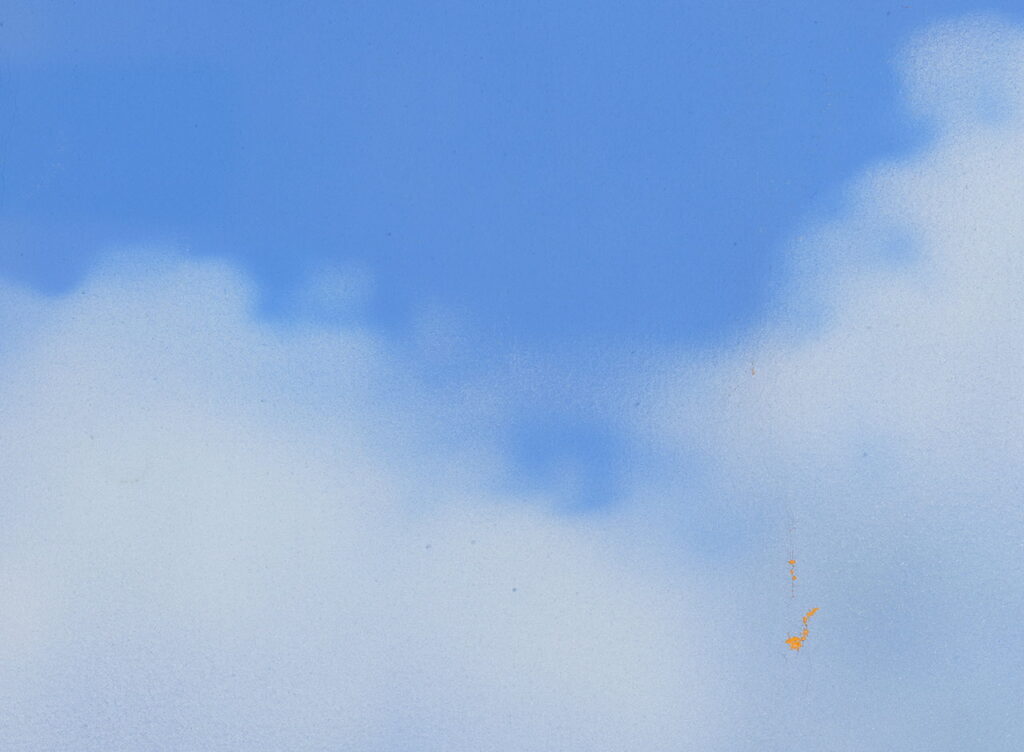 明るい青空の一部を背景に、白く大きな雲の端がふんわりとした質感で描かれた青空の特撮映画の背景パネルをクローズアップで捉えた写真