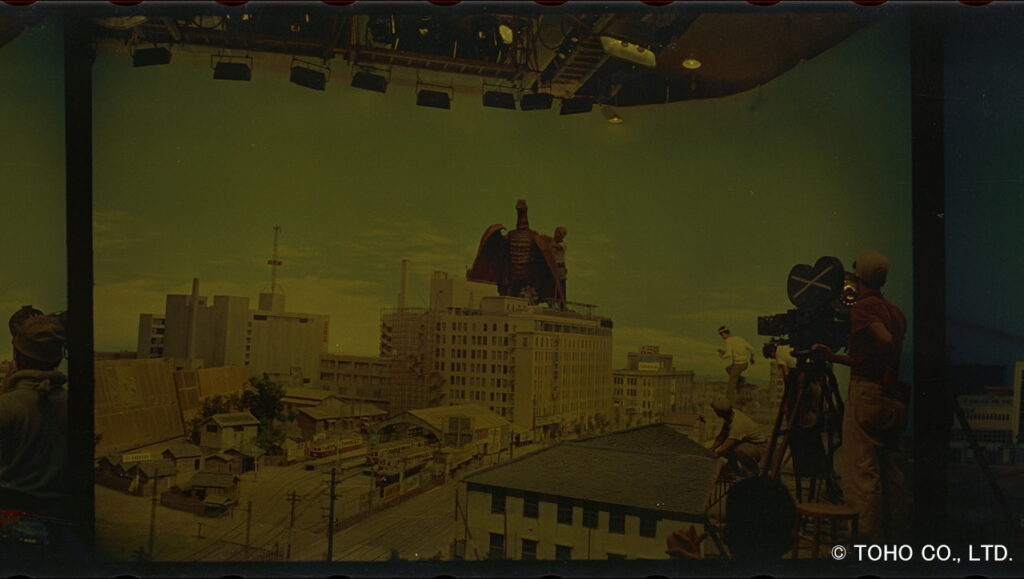映画の特撮スタジオにて、ビル群のミニチュアセットの上で撮影する様子を捉えた画像の色が暗く変色していることが分かる写真