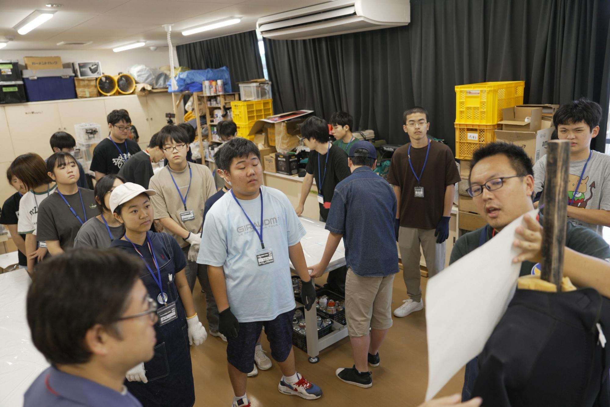 すかがわ特撮塾の活動で講師が着ぐるみの作り方について説明し、塾生たちが集まってそれを聞いている様子