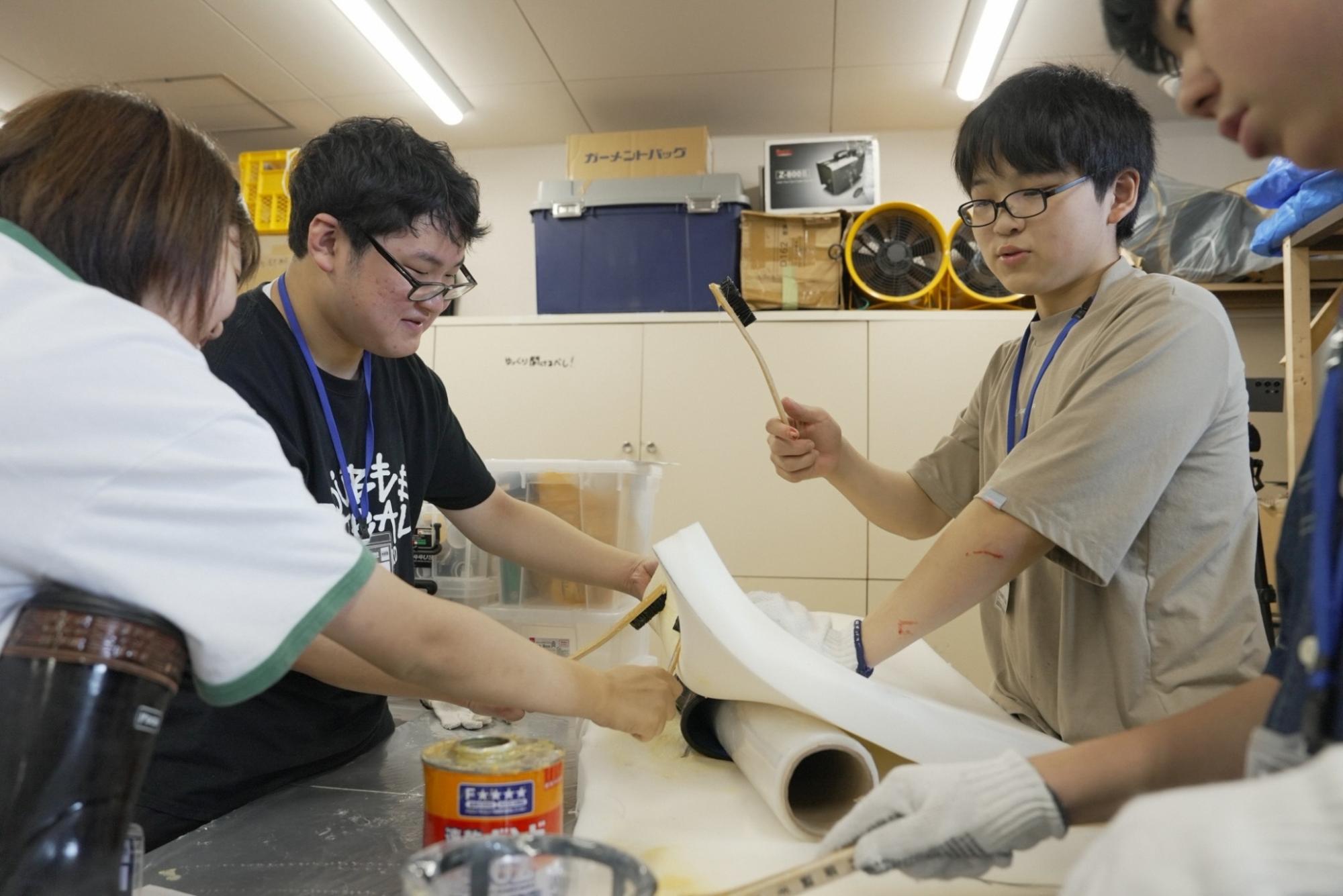 すかがわ特撮塾の活動で塾生たちが宇宙人の着ぐるみを制作している様子。写真は数人が協力してウレタンを長靴に接着している様子