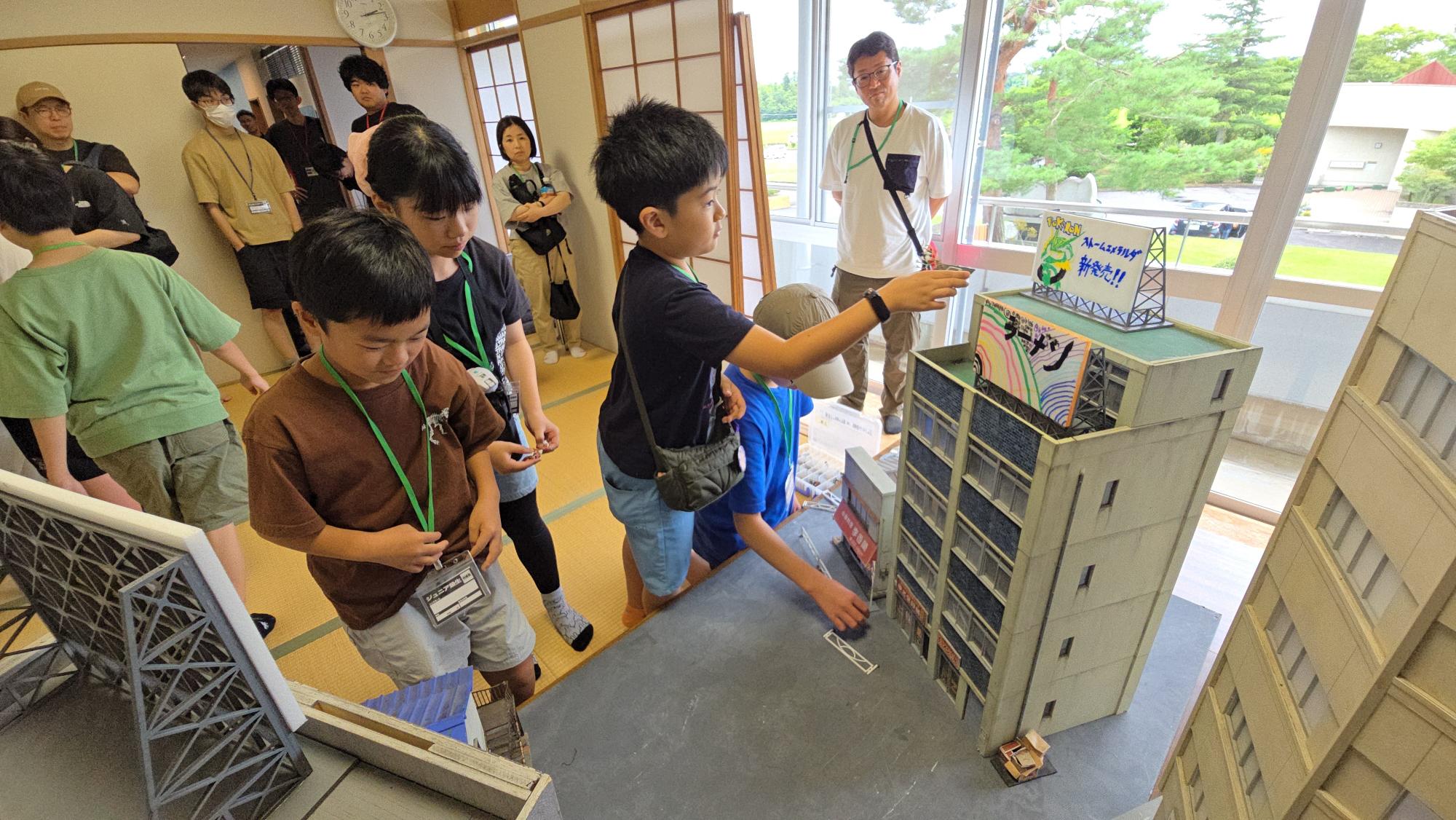 すかがわ特撮塾ジュニア塾生の活動で、自分たちで作った看板ミニチュアや小物をミニチュアセットの中に飾る様子