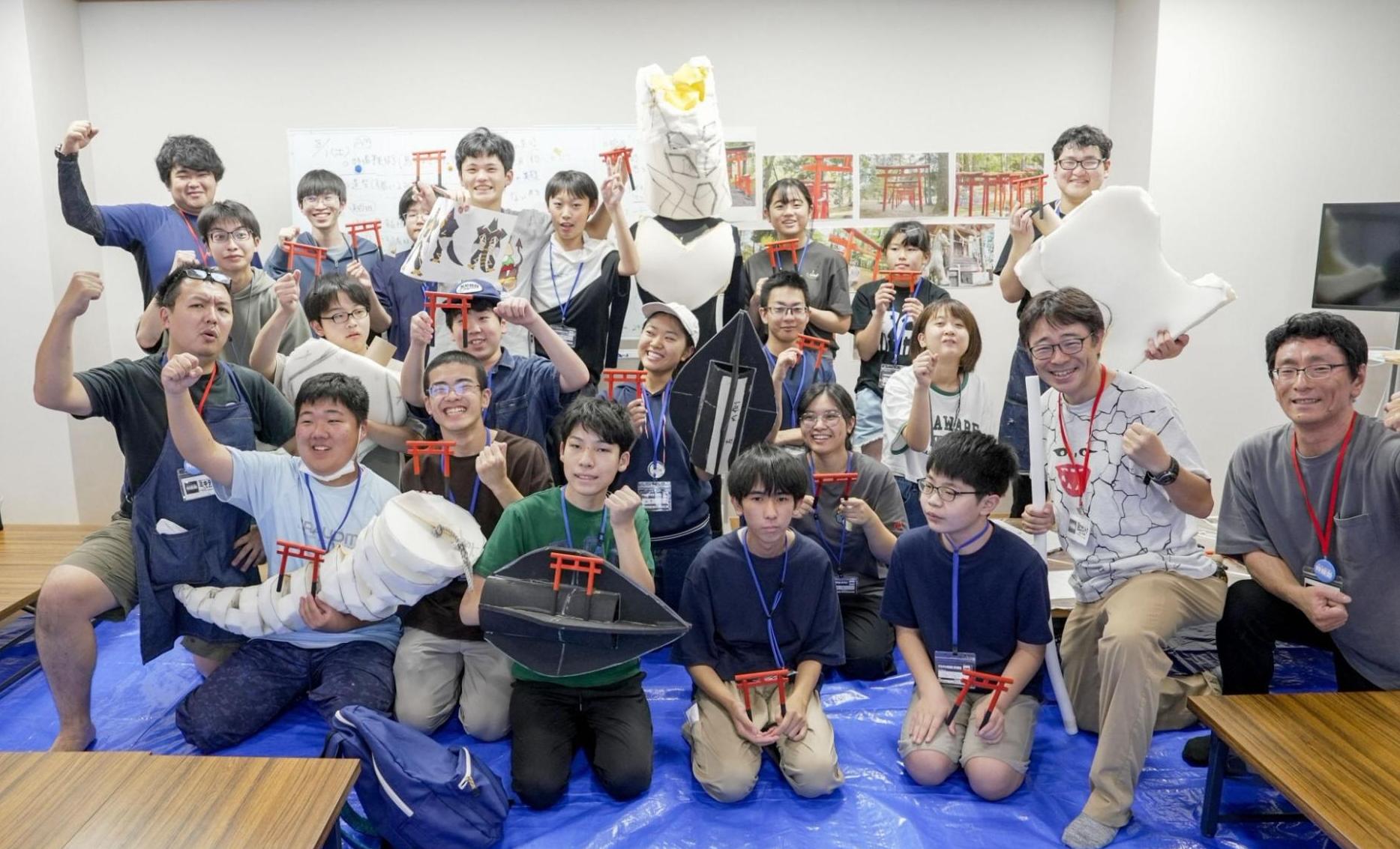 すかがわ特撮塾生たちが、自分たちが制作したミニチュアや宇宙人の着ぐるみパーツを手に集合している写真