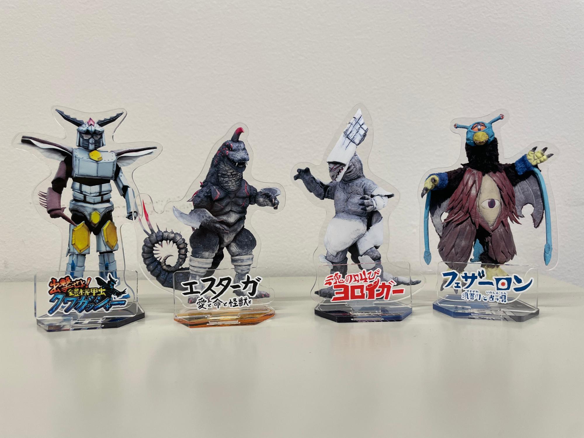 ヨロイガー、エスターガ、フェザーロン、クワガッシャーがそれぞれ印刷されたアクリルスタンドが横並びで置かれている写真