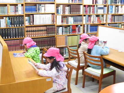 机に座って本を読んでいる写真