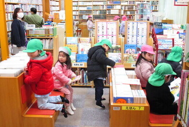 低いベンチに座って本を読んでいる子どもたちの写真