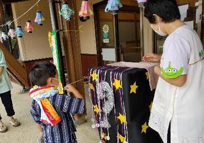 写真：くじ引きでひもを引こうとしているこども