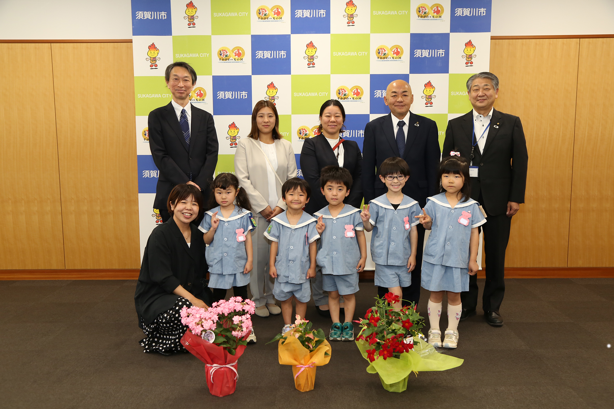 大寺市長（後列右2人目）、永瀬教育長（後列右）に鉢植えの花を贈る天泉こども園の園児たち