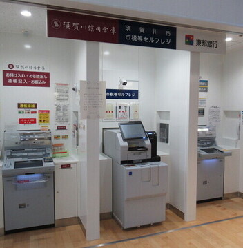 白い柱で区切られた区画に、須賀川信用金庫と東邦銀行のATMがそれぞれ1台ずつ、中央に市税等のセルフレジが1台設置された金融機関の共同出張所内観写真