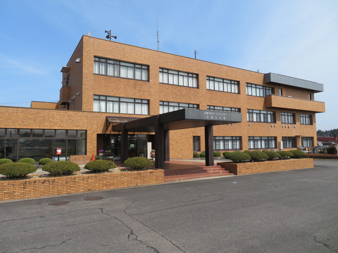 手前に植栽があり、入口前には広い雨除けが付いた、茶色のレンガ調の外壁ので3階建ての、岩瀬コミュニティセンター外観写真