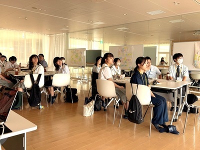 広い教室で複数の学生が机に着席して前方の説明を見つめ、落ち着いた雰囲気の中で学習に取り組んでいる様子が伝わる写真