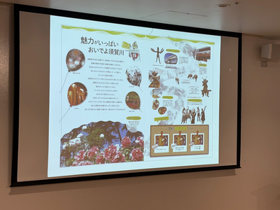 スクリーンに地域の名所や特産、行事を紹介する写真や図表が配置された観光案内のスライドが投影されている写真