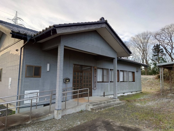 瓦屋根と薄いグレーの外壁で平屋建ての集会施設の外観写真