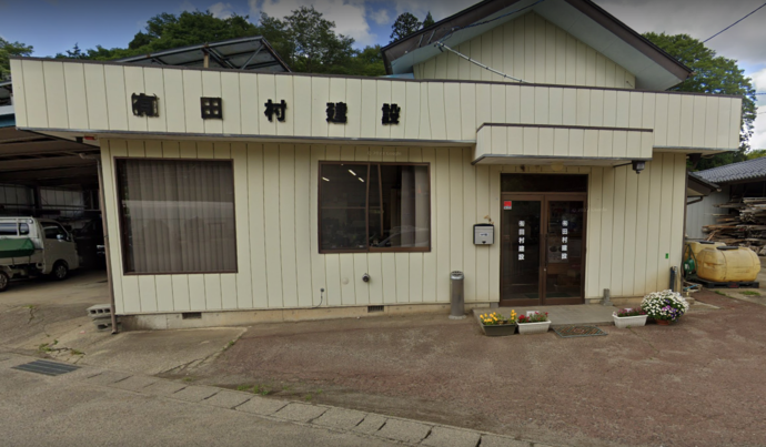 「有限会社田村建設」と黒い文字の看板が掲げられたクリーム色の外壁で平屋の建物の外観写真