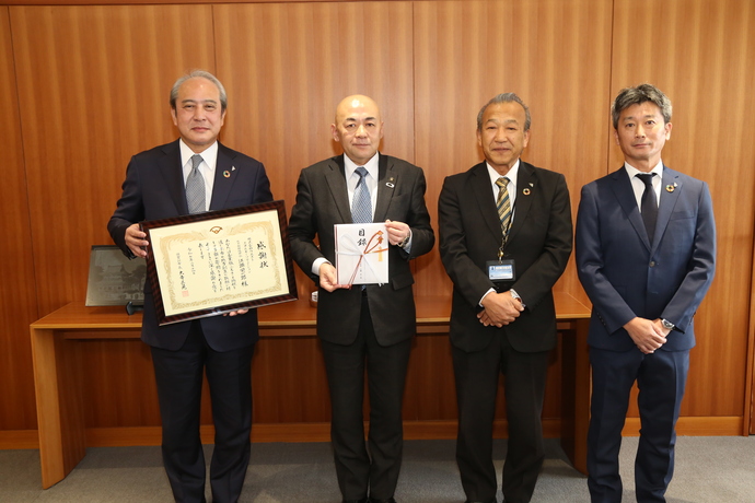 執務室内で左から感謝状を持った対馬将夫取締役、目録を持った大寺市長、 神定和弘福島県エリア担当リーダー課長、 那須野崇福島県担当課長が並んで撮影した記念写真