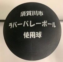 黒色のゴム製ボールに、「須賀川市 ラバーバレーボール 使用球」という白い文字が三行にわたってプリントされている、競技専用のボールを真上から捉えた写真