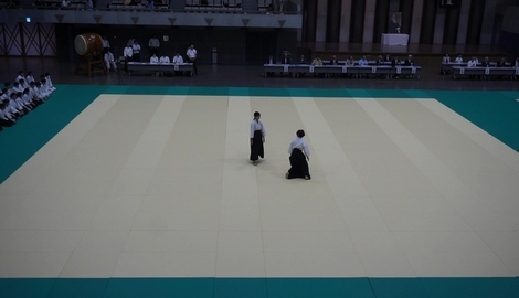 周りが緑色のベージュのマットが敷かれた広い会場で、袴姿の2人の試合が行われている様子の写真
