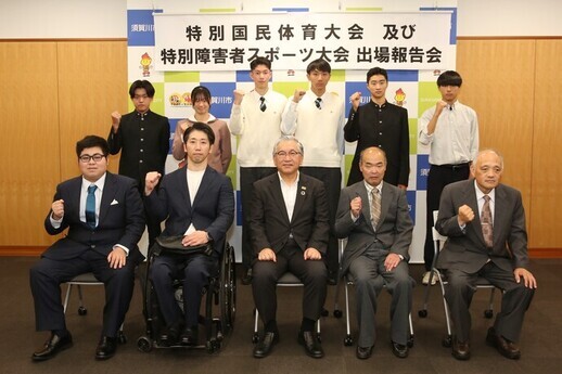 「特別国民体育大会及び特別障害者スポーツ大会出場報告会」の横断幕が掲げられたバックパネルの前で、前列に橋本市長を中央に4人のスーツ姿の選手が並んで座り、後列に制服姿の6人の男女の選手が立って並び、選手たちは右手のこぶしをあげたポーズをした記念写真