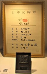 「日本記録章」と題された成績記録が、金色の額縁に入って、黒い小さな盾と一緒に展示されている写真