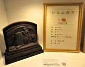 右側に金色の額縁に入った「日本記録章」、左側に人物のレリーフが施された飾り板が展示されている写真