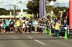 「須賀川市文化センター」の看板が立つ道路上で、ゼッケンを着用した大勢のランナーたちがスタートラインに整列し、係員の指示を聞きながら号砲の瞬間を今か今かと待ちわびている、マラソン大会のスタート直前の風景写真