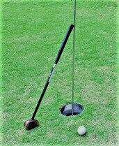 パークゴルフ専用のクラブとボールがピンカップの横に並んでいる写真