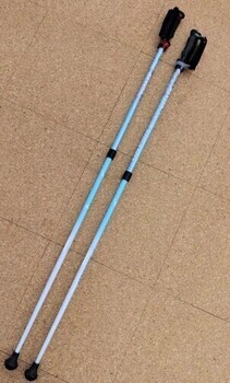 白と水色の配色で、黒のグリップが付いたポールウォーキング用のポールが2本並んで床に置かれている写真