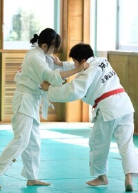 柔道着姿で組み合っている2人の女子学生の写真