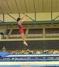 トランポリンで高くジャンプしている選手を横から写した写真