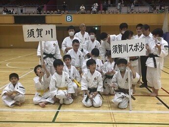 体育館で、白い道着を着た子どもたちが、「須賀川」「須賀川スポ少」のプラカードを持ち、集まっている写真