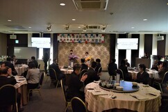 「令和5年度須賀川市スポーツ推進委員連絡協議会祝賀会」の看板が掲げられた会場で、円卓を囲んだ多くの出席者たちが拍手を送る中、正面のステージ上で花束を贈呈された二人の女性が並んでいる写真
