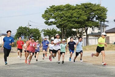 屋外のトラックをたくさんの子どもが走っている、円谷ランナーズの活動風景の写真