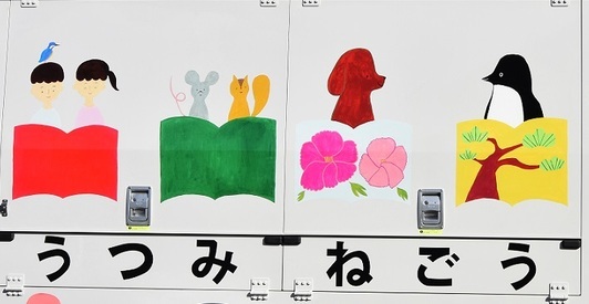 赤と緑と黄色の本から子どもや動物たちが顔を出して並ぶ、車体に描かれたカラフルなイラストの写真