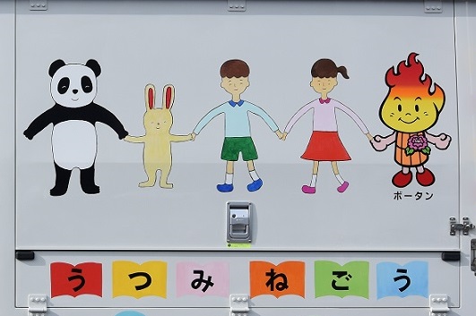 パンダやウサギ、男女の子どもとボータンが手をつないで並ぶ、車体に描かれたカラフルなイラストの写真