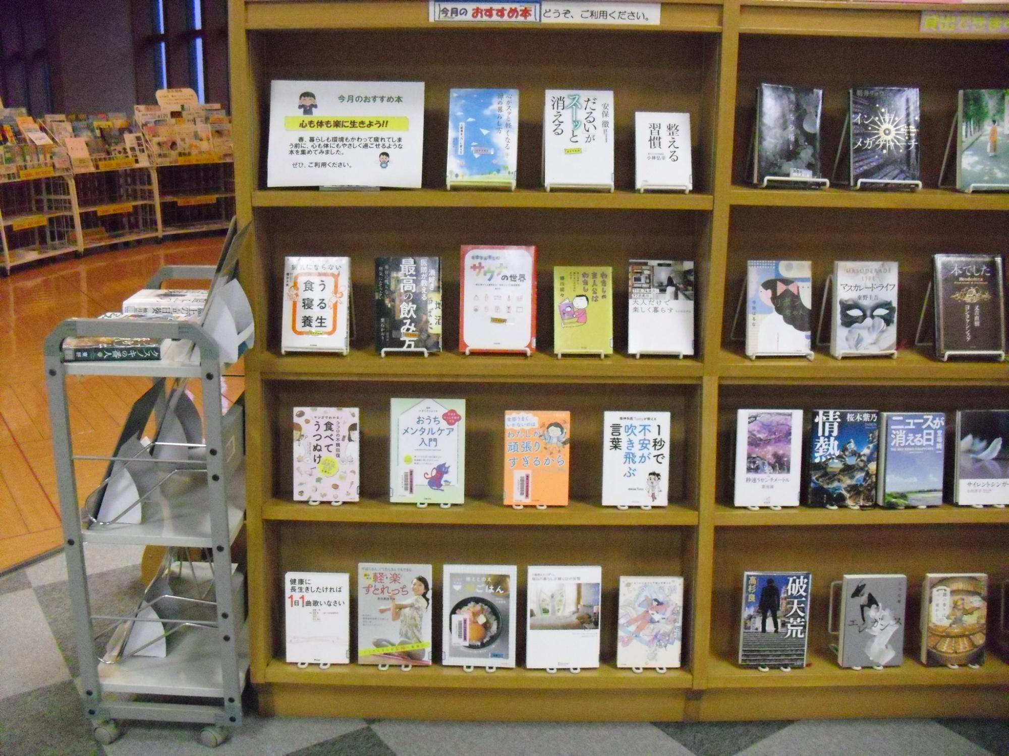 図書館の木製棚に4月のテーマに関する展示図書が並ぶ様子の写真