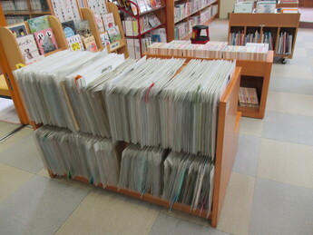 上下二段の低い木製棚に、紙芝居などがぎっしりと収納されている様子の写真