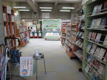 書棚が並ぶ落ち着いた図書館内で絵本や児童書のコーナーが中央に展示されている様子の写真