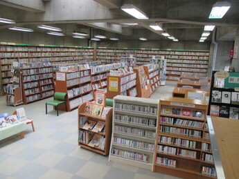 広い図書館内に整然と並ぶ書棚と閲覧席が奥まで続き、多様な本がぎっしりと配置された様子の写真