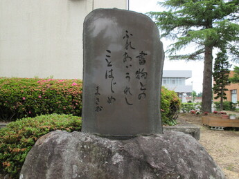 庭園の一角で大きな岩の上に据えられた石碑が刻まれた文字を静かに見せ緑に囲まれて佇む写真