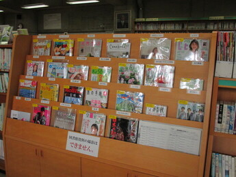木製の傾斜した棚に、様々な分野の雑誌が、表紙が見えるように並べられている写真