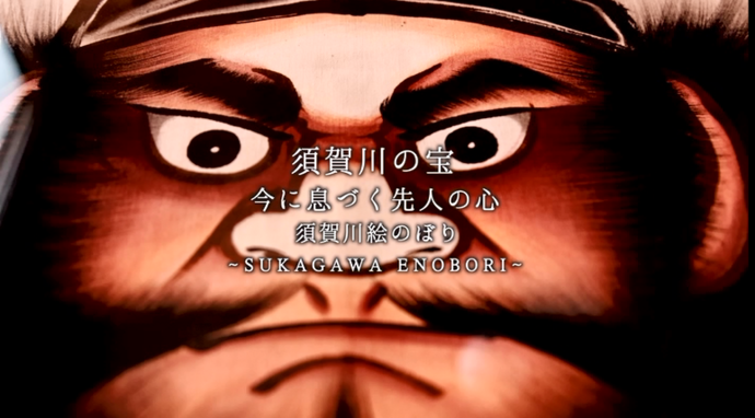 「須賀川の宝 今に息づく先人の心 須賀川絵のぼり 〜SUKAGAWA ENOBORI〜」という白い紹介テキストが、力強い眼差しと太い眉が印象的な武者の顔を大きく描いた伝統的な絵のぼりのアップに重なっている写真