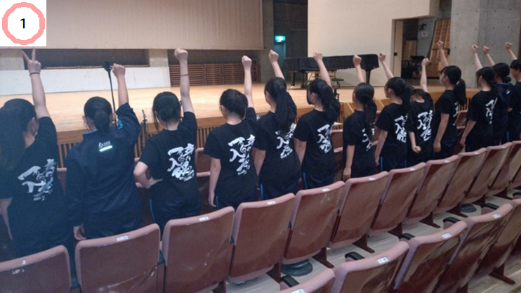 複数の中学生が後ろを向いて右手を挙げて整列している写真