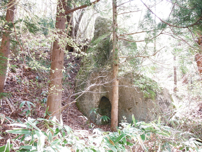 林の中に、小さな穴があけられた大きな岩がある、くぐり石磨崖仏の写真