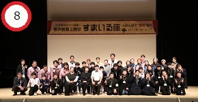 「すまいる座 無声映画上映会」という看板が掲げられたステージ上で、揃いのジャンパーや黒い衣装を着た多くの参加者たちが並んで笑顔でポーズをとっている、イベント終了後の集合写真