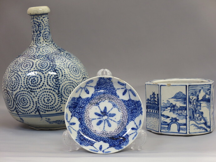 渦文様の大壺と花文を中心に配した皿、風景図を面取り状に描いた容器の3点が並び、繊細な藍色の意匠が際立つ長沼焼の写真