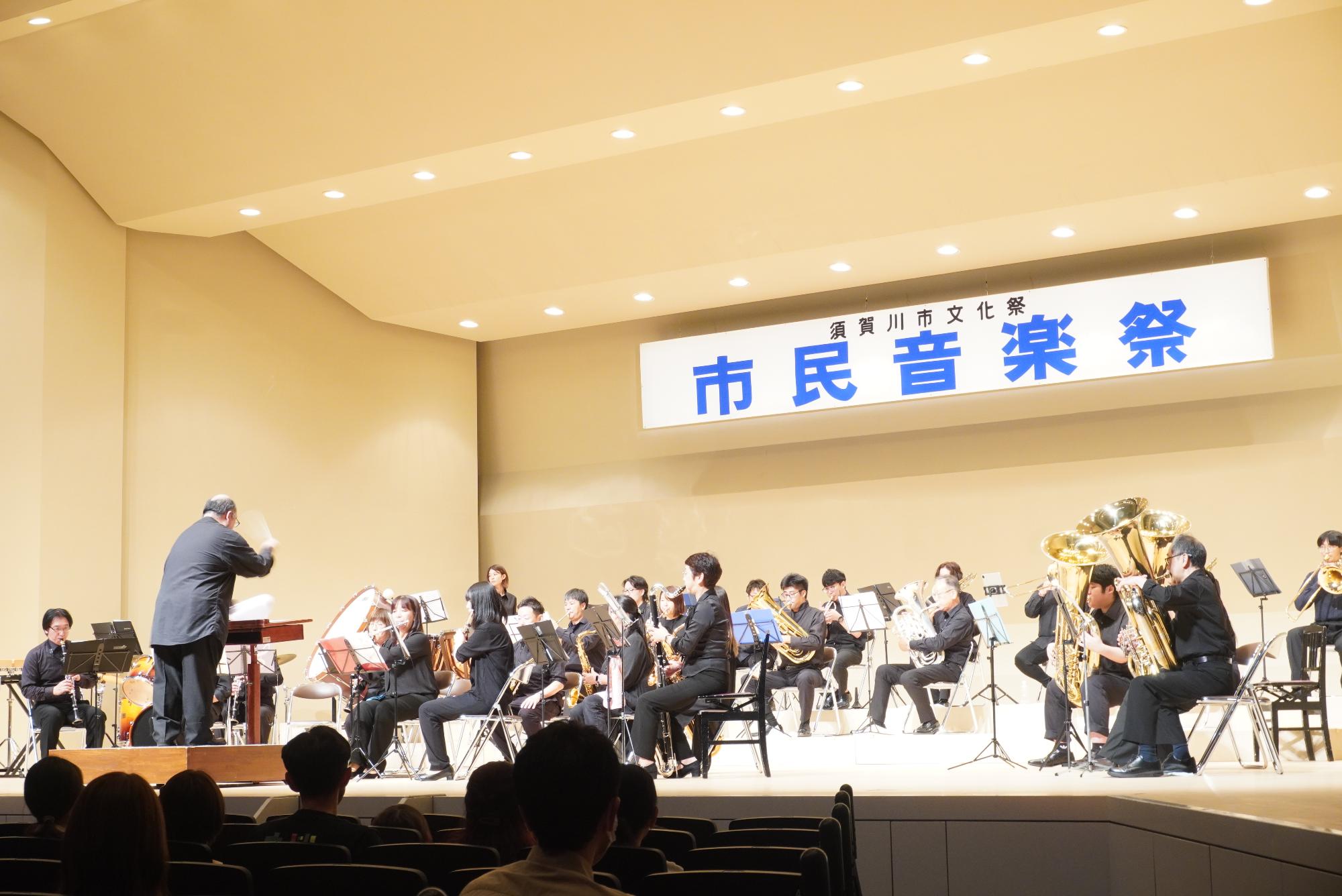 指揮者に合わせて20人程度が演奏をしている画像